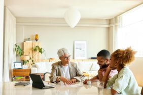 A man and woman talking to a real estate agent while using one of the best real estate websites
