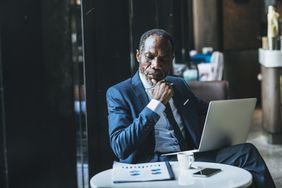A man with a laptop looking at papers