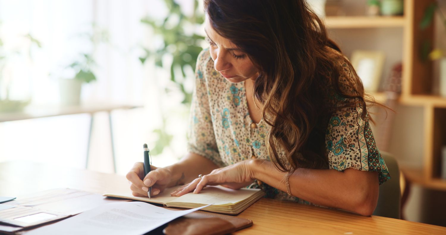 Woman working at desk writing in notepad