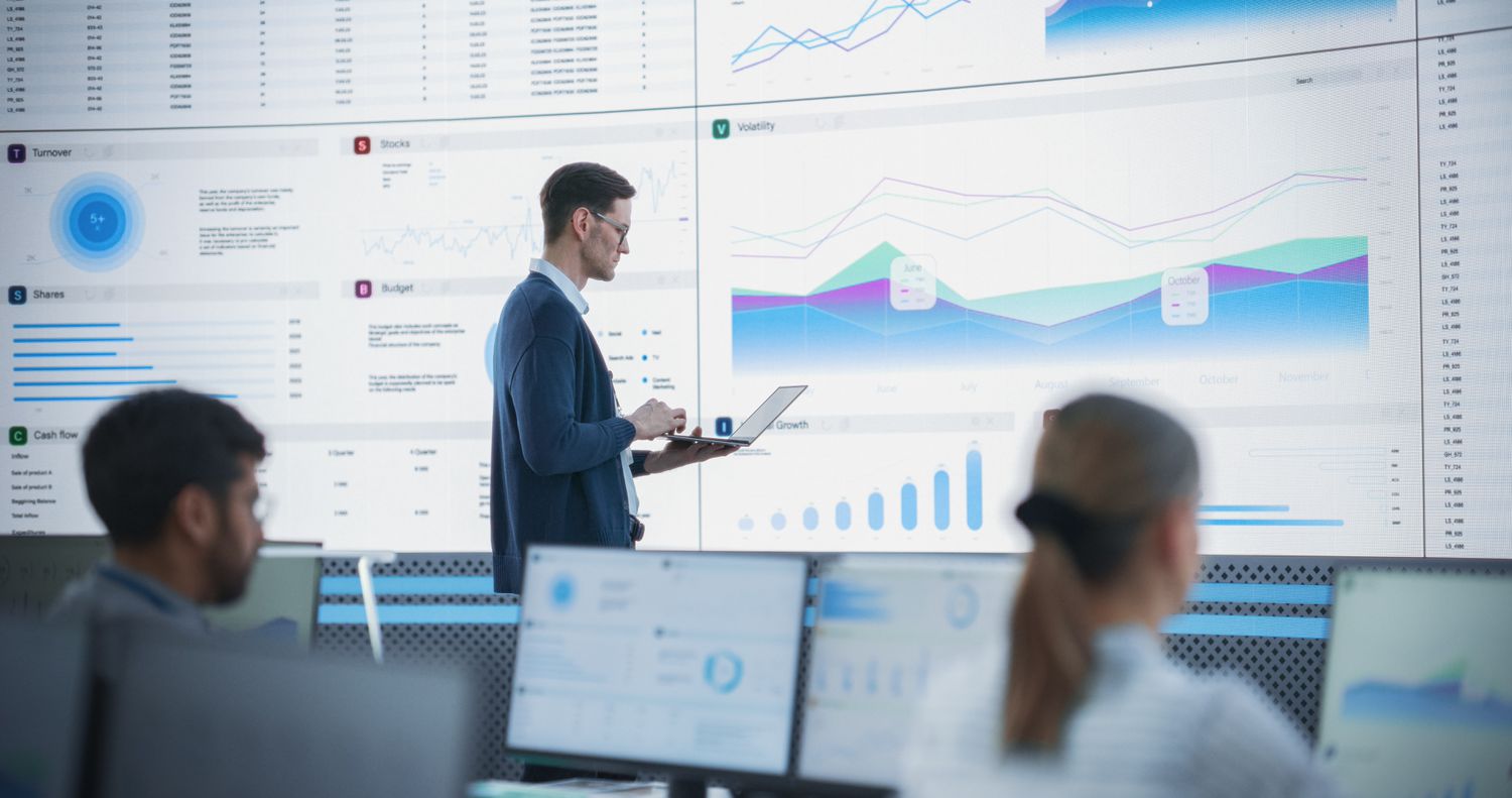 A senior financial analyst reviewing information and reports on big digital screen in modern monitoring office.