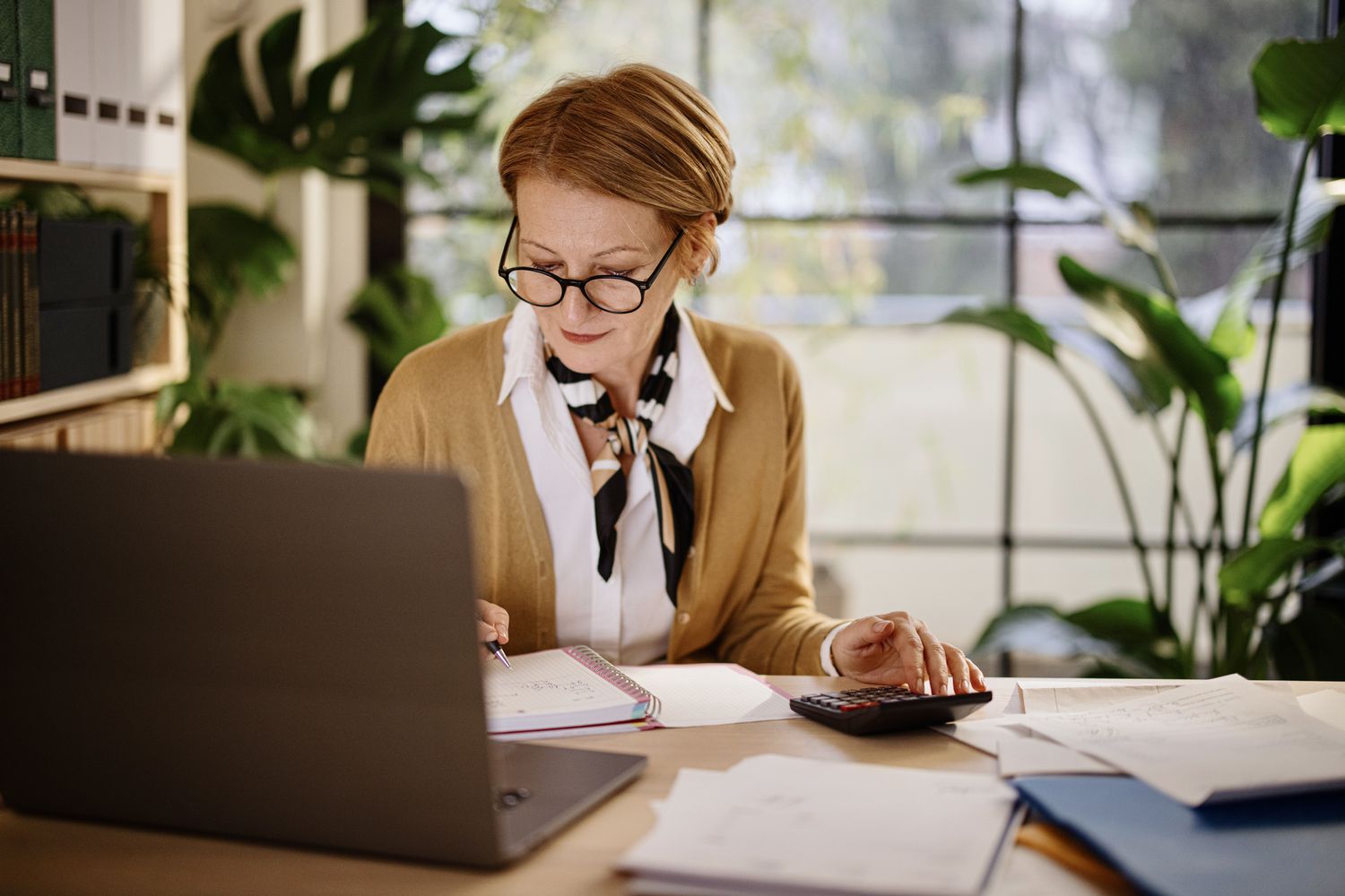 Worker at a desk with a calculator, looking at a notebook