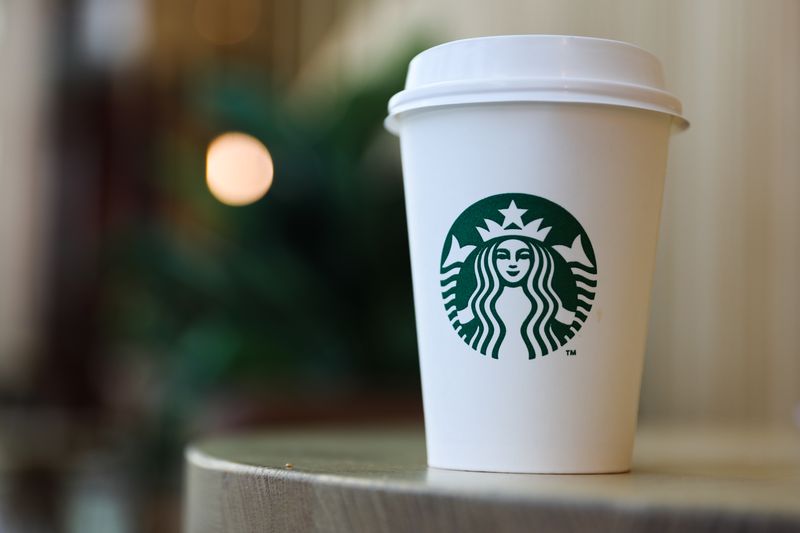 A coffee cup displaying the green Starbucks logo is placed on a table.