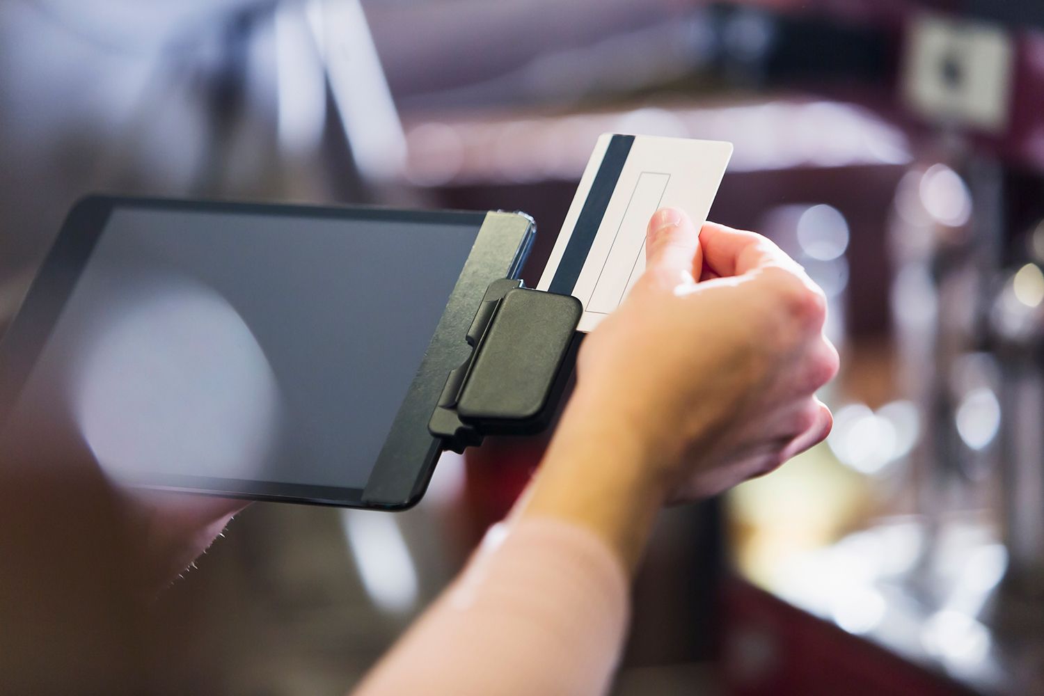 Hand of woman sliding credit card through reader