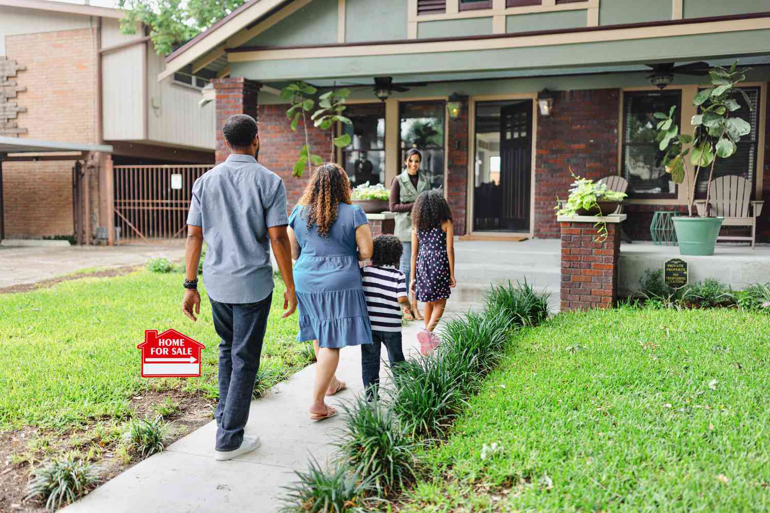 A family with a real estate agent outside of a home