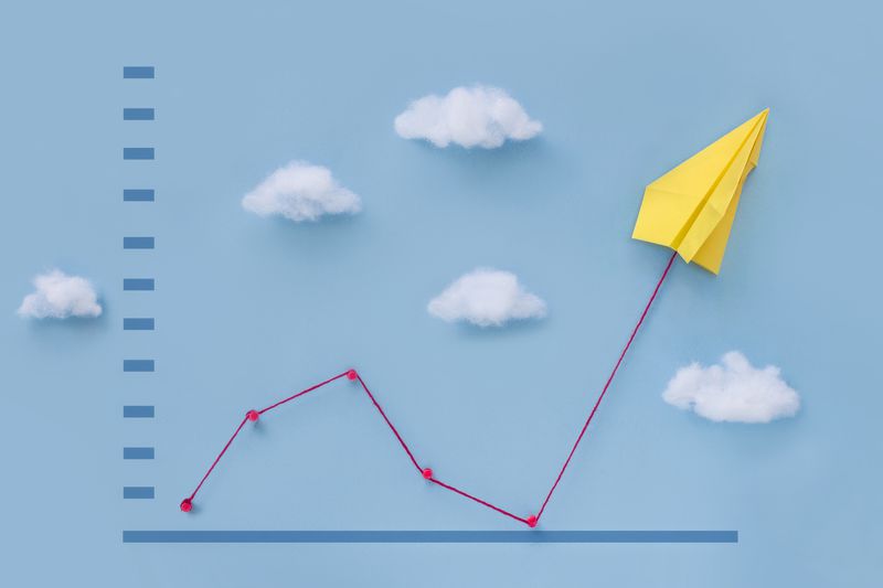 A sales graph background with origami airplane moving up.