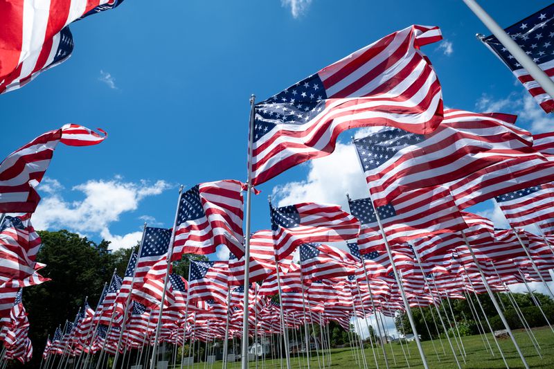 Multiple American flags flying on poles outside