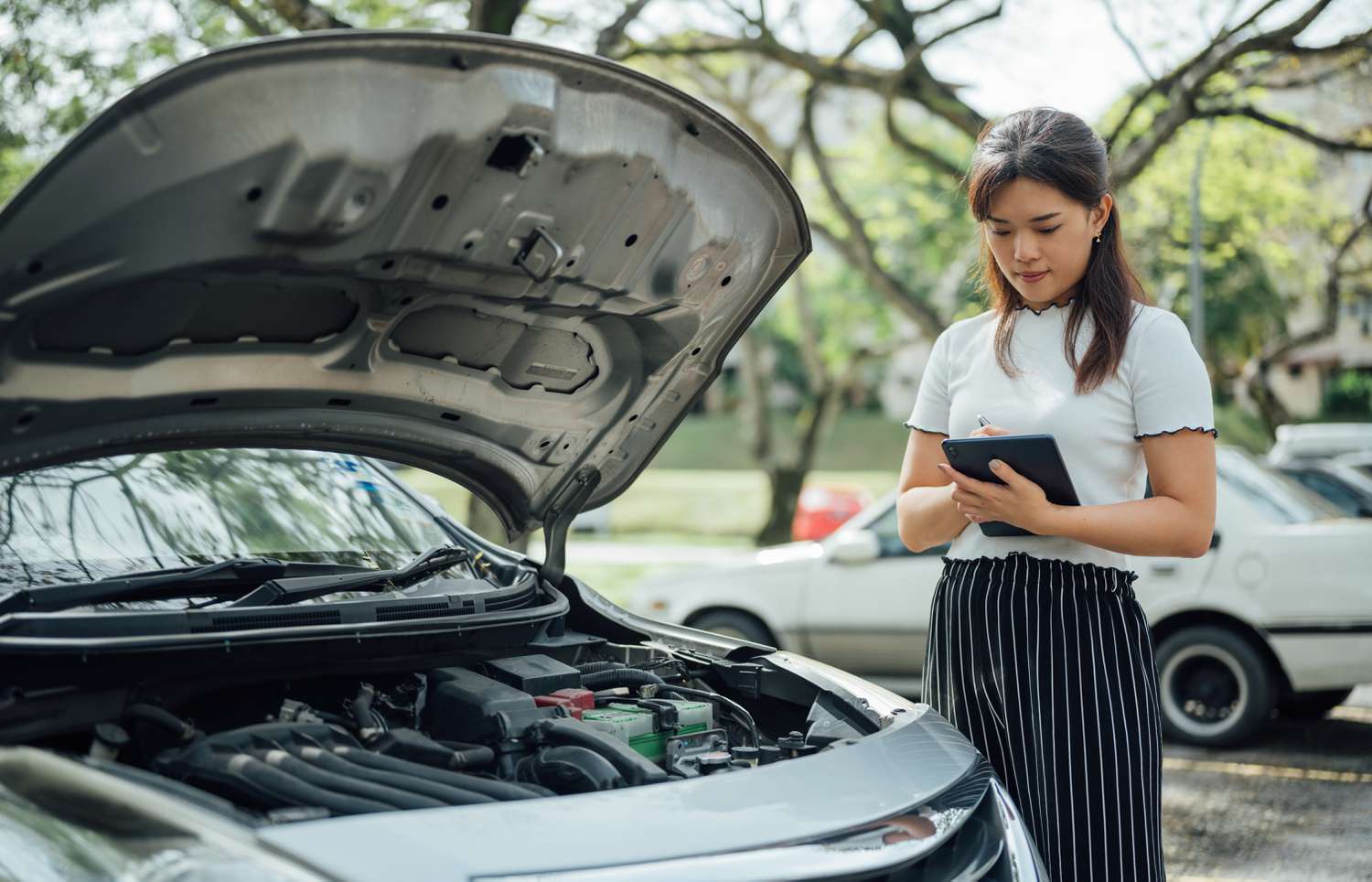 Automobile insurance adjuster uses digital tablet to inspect damage to vehicle.