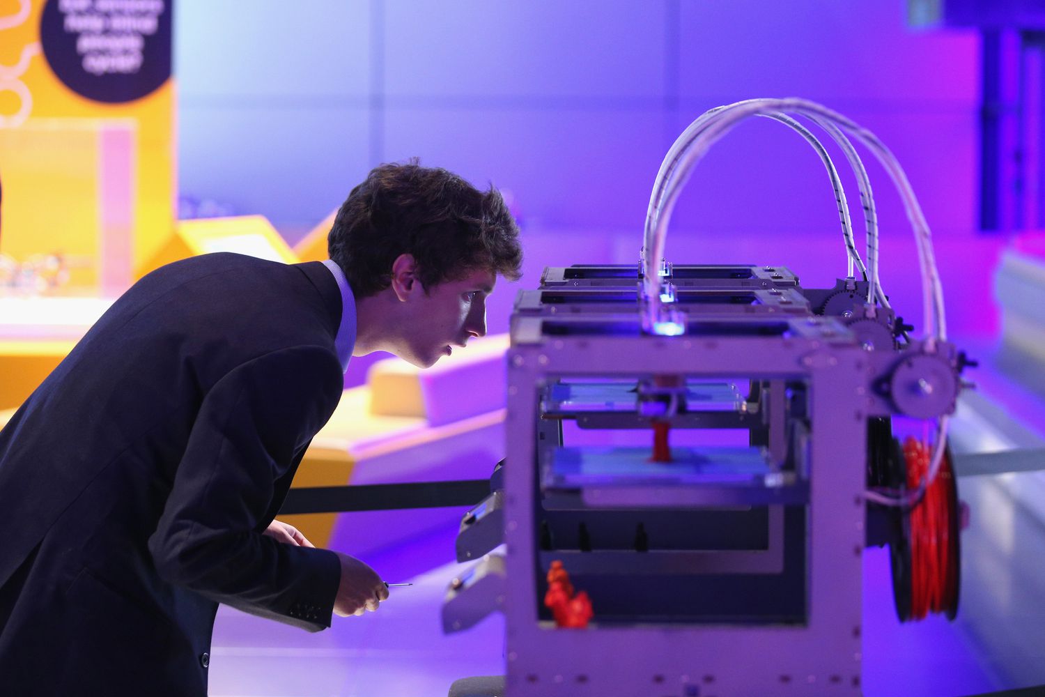 A technician checks on a 3D printer as it constructs a model human figure.