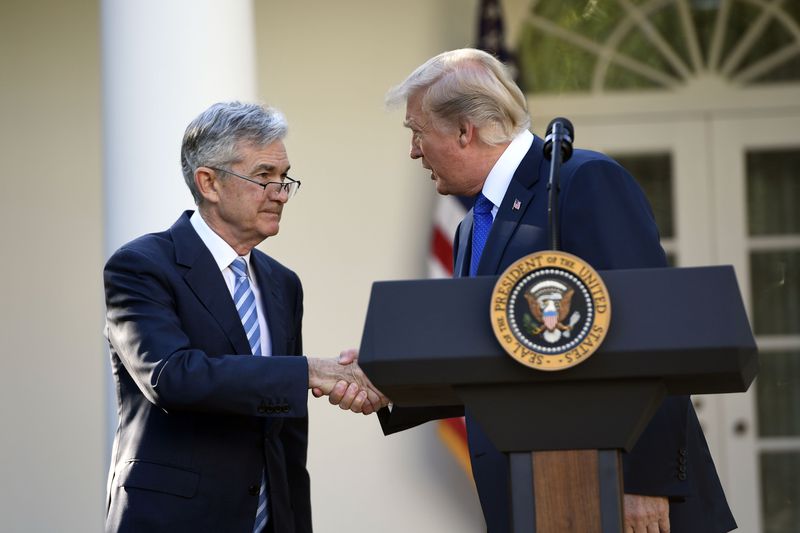 Donald Trump and Jerome Powell shake hands behind a podium with the presidential seal on it outside the White House.