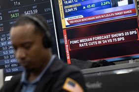 A trader sits in front of TV screens displaying information about the Fed's rate cut announcement.