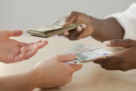 Picture of hands from two people exchanging dollars for euros.