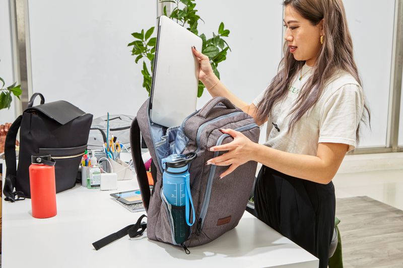 Person putting a laptop in the Kroser Laptop Backpack with Charger