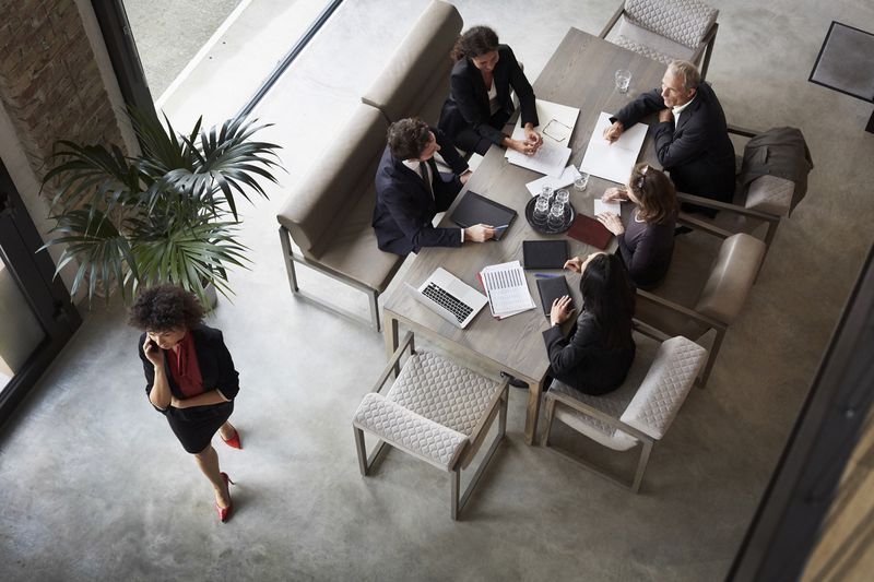 Aerial view of business people in a meeting with papers and a laptop on the table