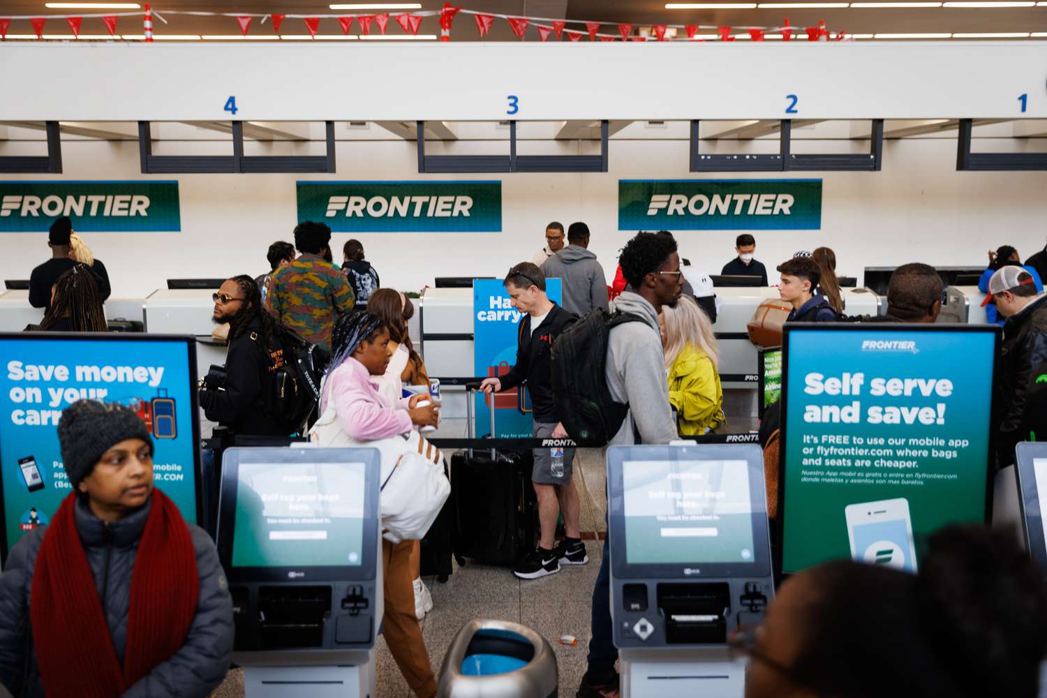 Travelers check in to fly Frontier Airlines in December 2023. 