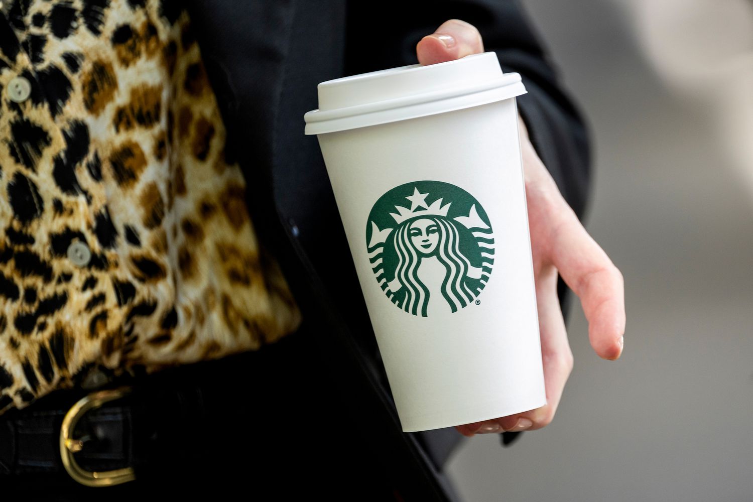 Pedestrian holds a Starbucks cup.