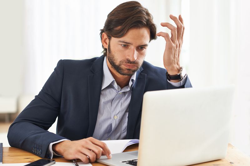 Frustrated Man Looks at Laptop Screen 