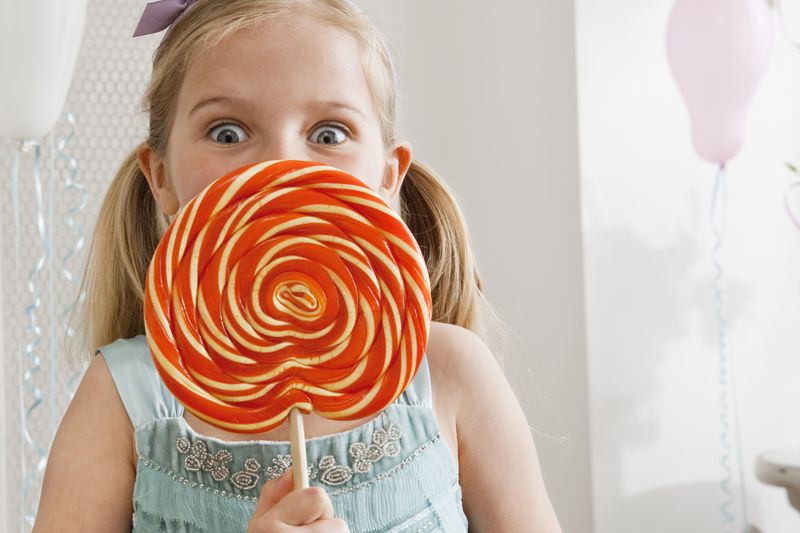 Little girl with fancy lollipop the size of a plate