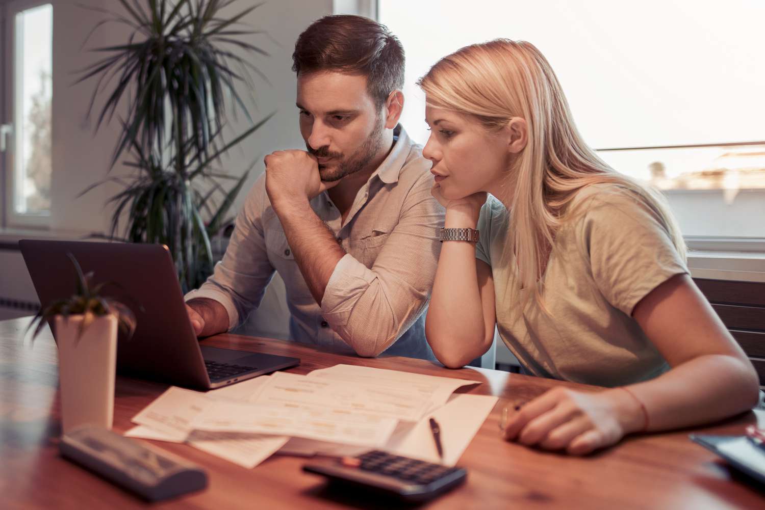 Couple in their 30s sitting at home and looking at mortgage rates on a laptop