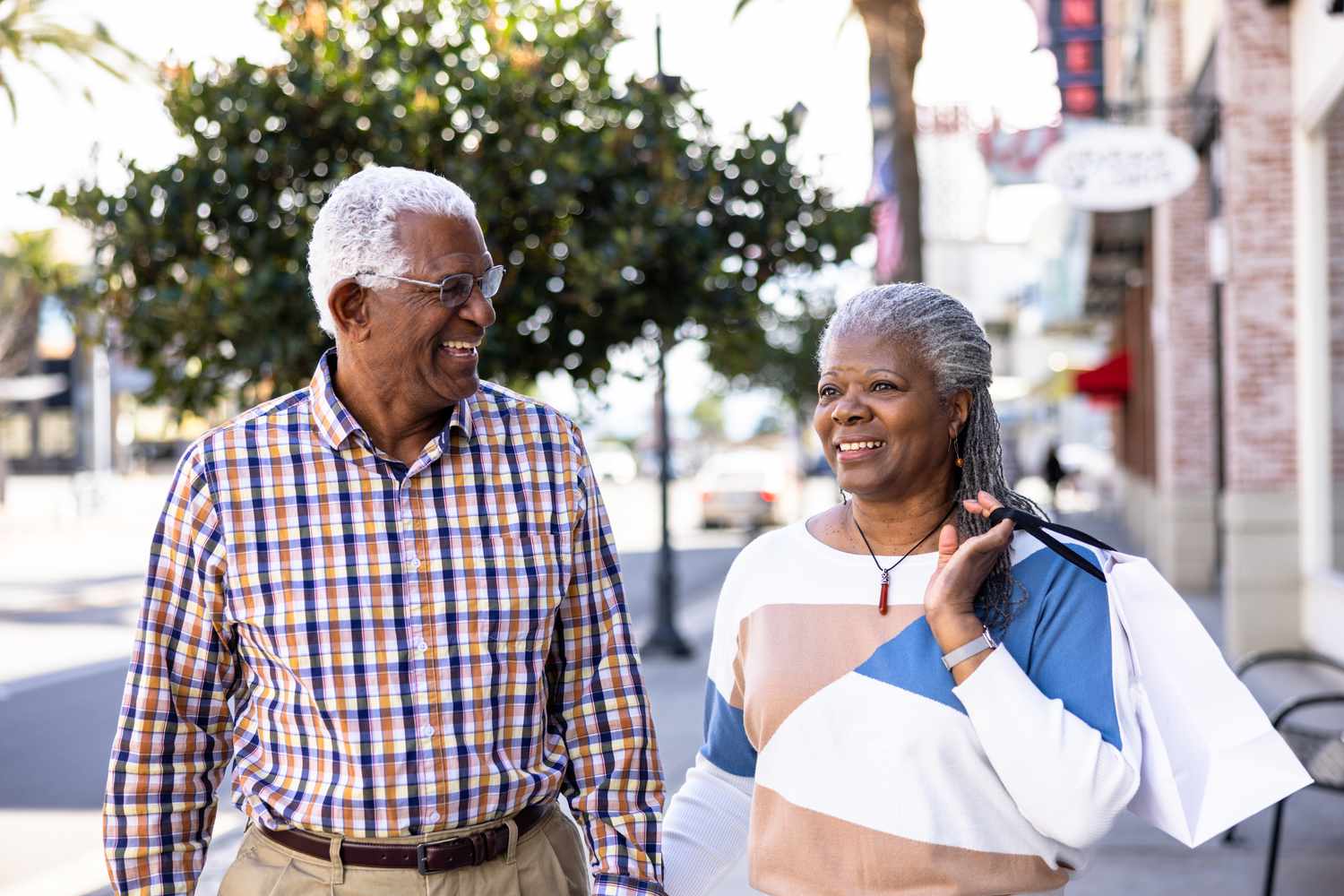 A senior black couple shopping downtown during the daytime.
