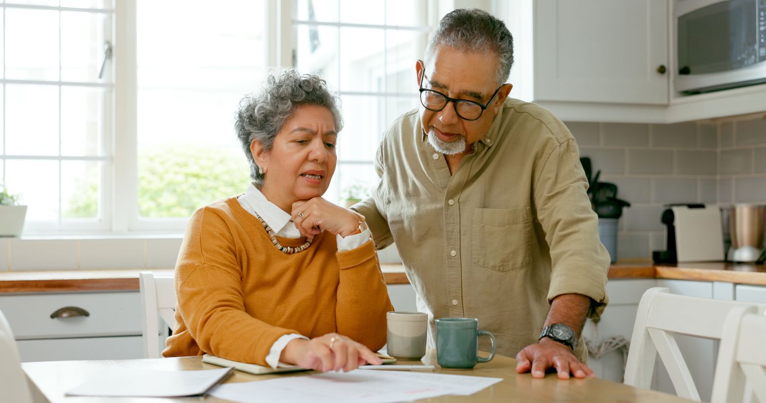 A couple discuss bills in the kitchen.