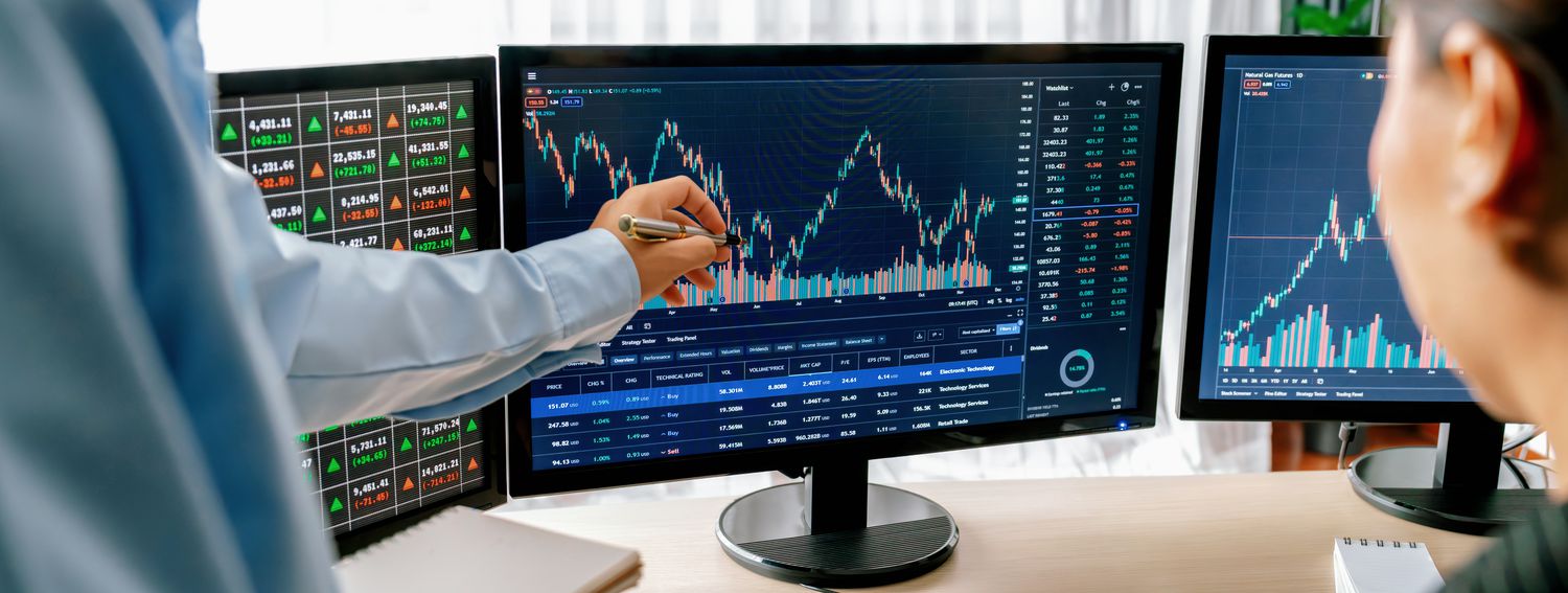 A trade manager points out a symmetrical distribution pattern on a computer monitor as they train a junior trader.