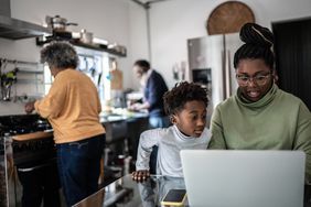 Mother and son using laptop in the kitchen at home