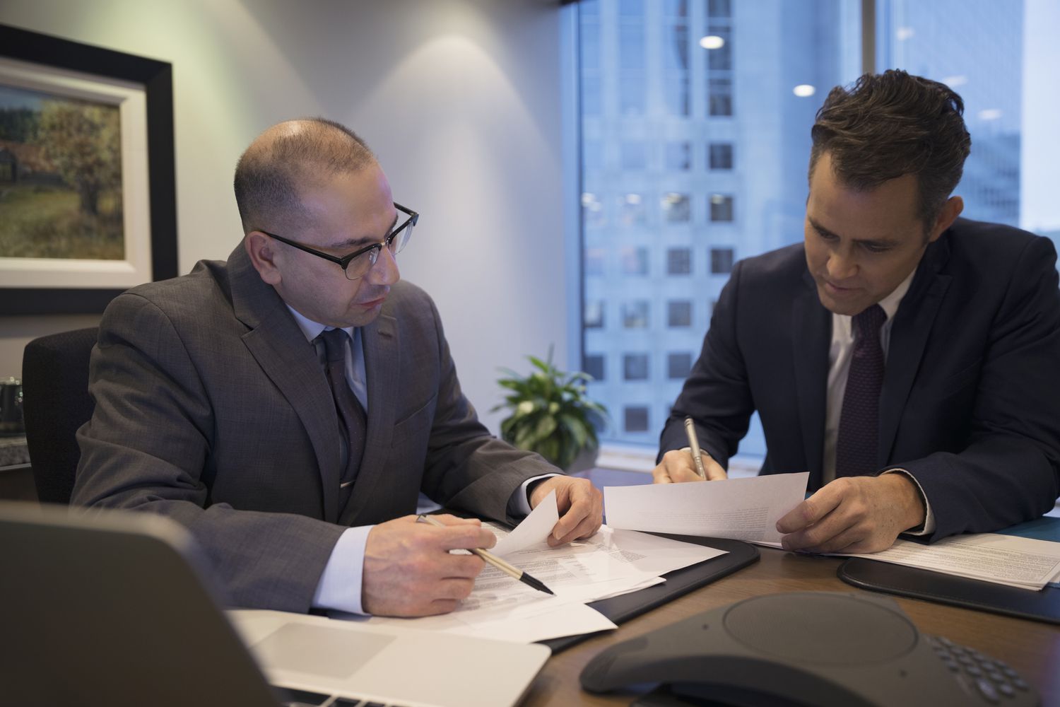 Male lawyers reviewing and signing contract in conference room