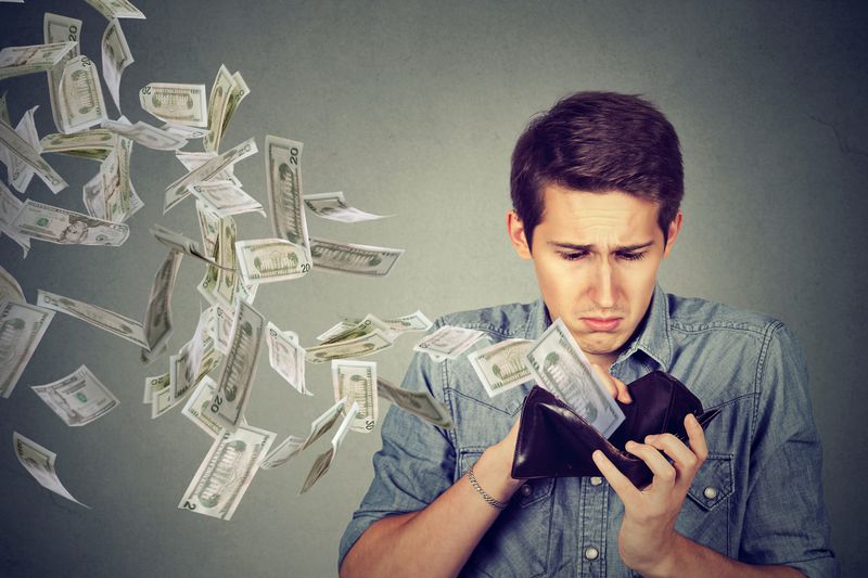 A man with money flying out of his wallet
