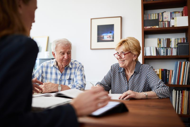 Senior couple planning their investments with financial advisor. Retired couple meeting with a female financial advisor at home.