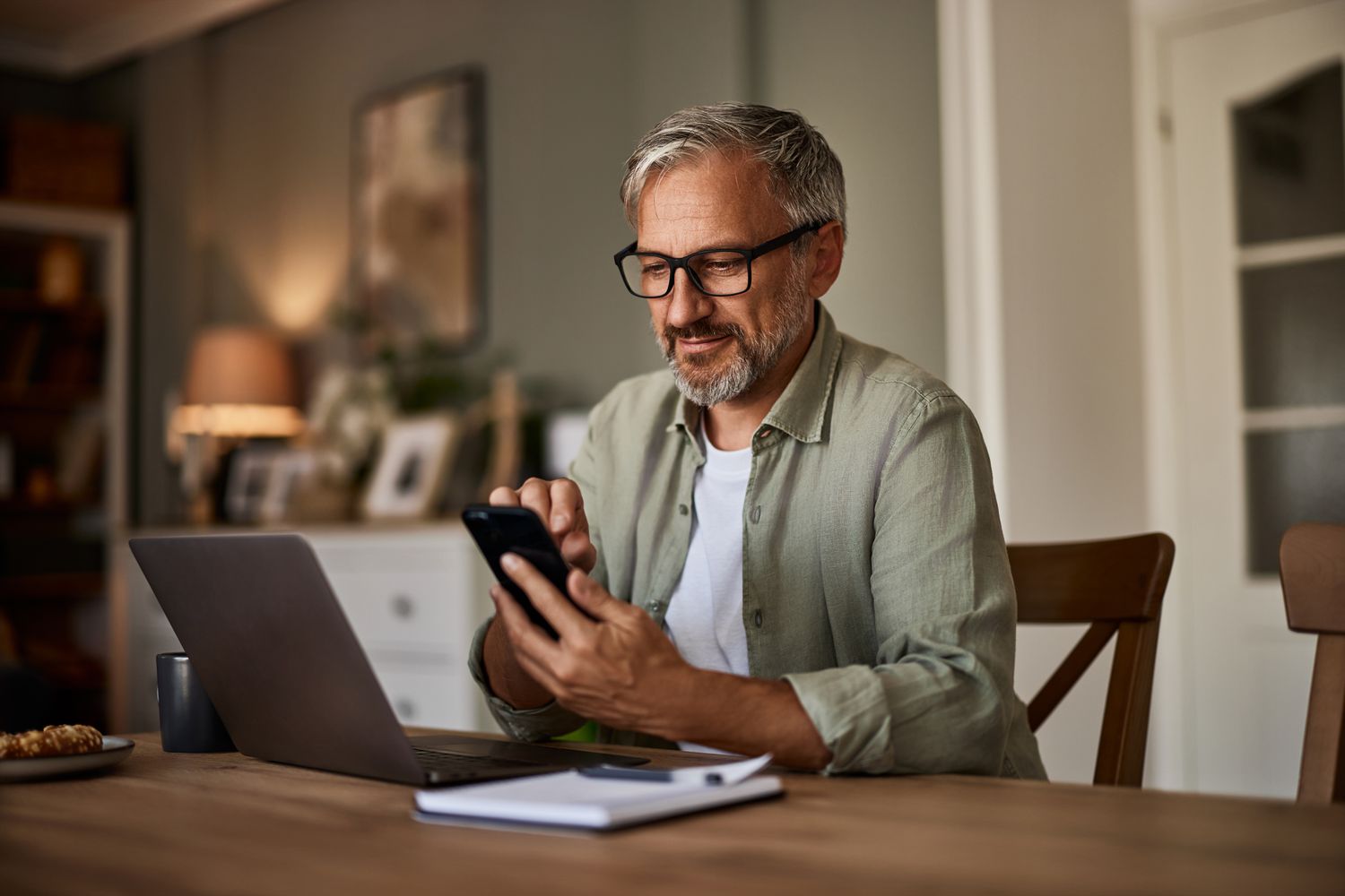 A man sitting at a desk uses a smart phone.