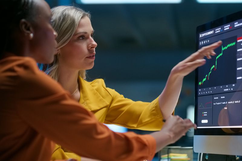Business people looking at a computer screen with stock market information.