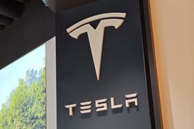 The white Tesla logo is seen on a black wall inside a store in China.