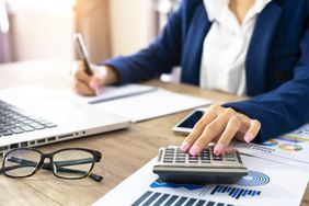 Business woman using a calculator to calculate the numbers on her desk in an office