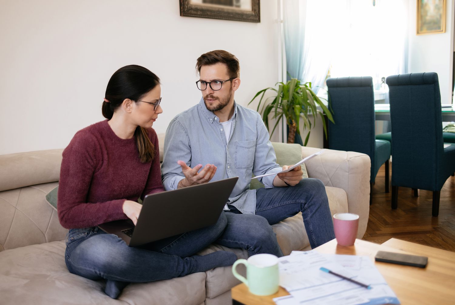 A couple on a couch with a laptop and papers
