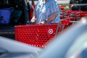 A shopper stands near a vehicle with a Target shopping cart.