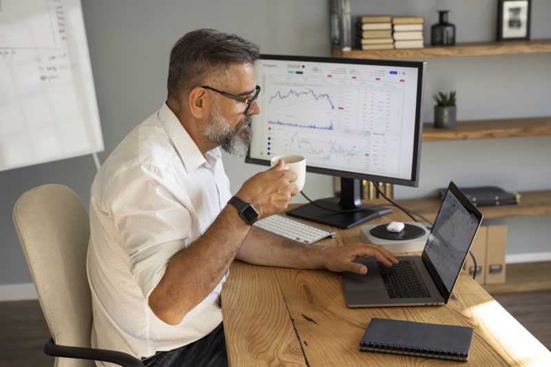 Investor sipping coffee at the table while deciding which holdings to sell to gain favorable tax treatment.