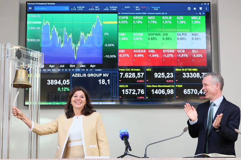 A CEO rings the opening bell of a stock exchange as the company's CFO claps and the pair are flanked by stock index data on a screen.