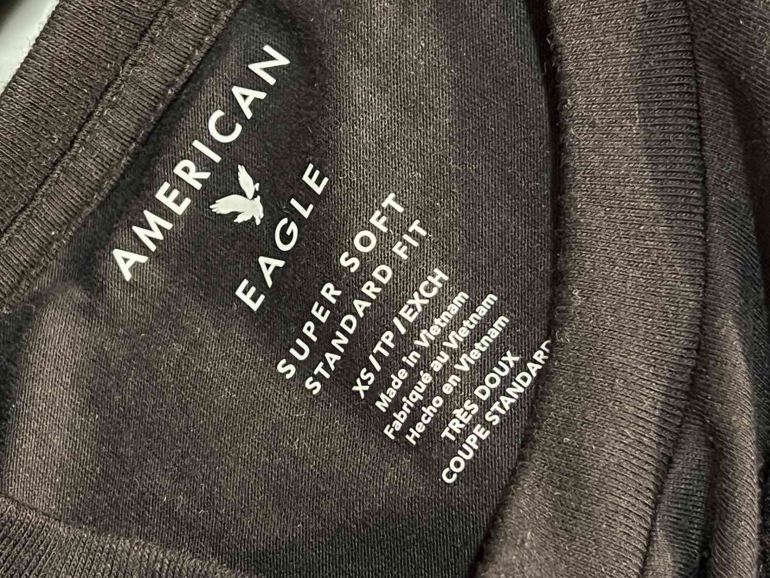 The inside of a black shirt says "American Eagle, Super Soft Standard Fit" with other size and manufacturing information.