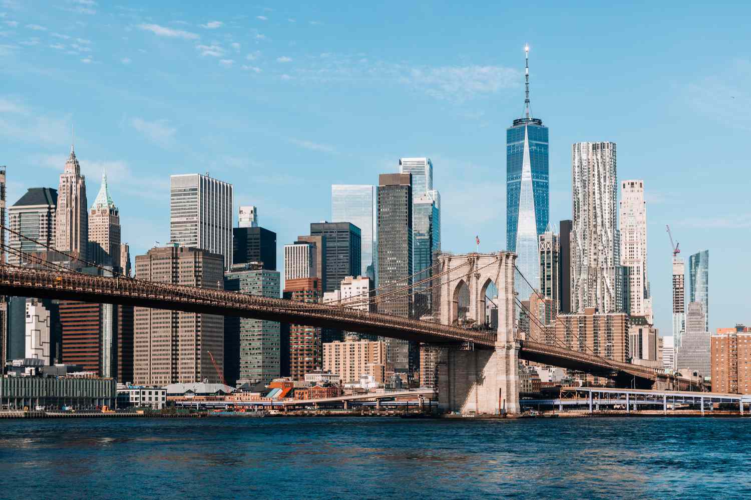 A view of the New York City skyline including the Brooklyn Bridge and One World Trade Center.