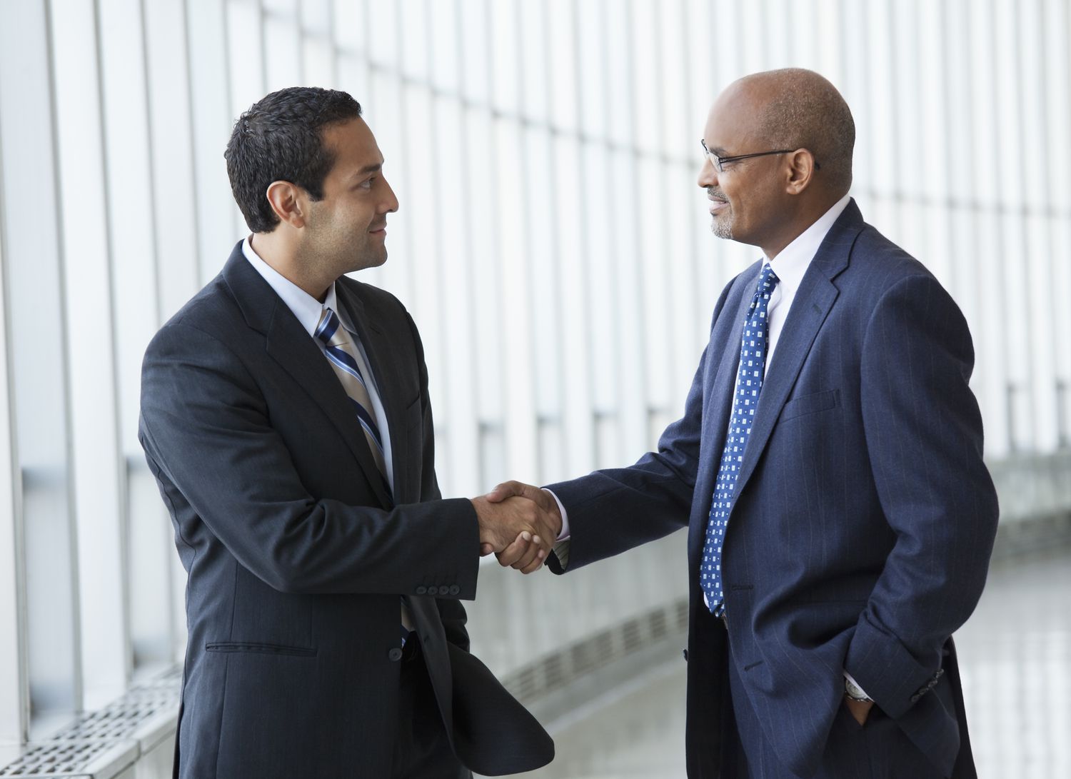 Two men shaking hands in a hallway of an office building