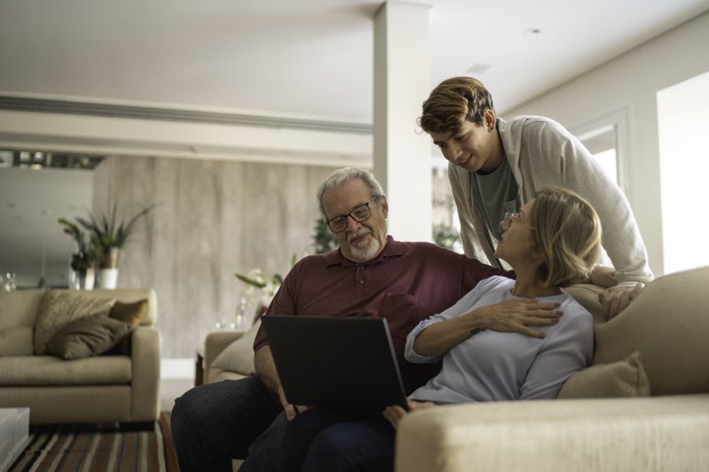 Young man looking at a laptop with grandparents