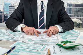Businessman making calculation financial annual report and after fill 1040 tax form. 