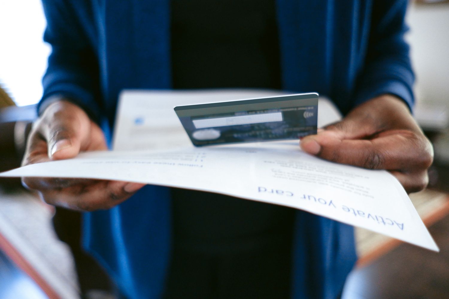 Cropped person holding credit card and paper
