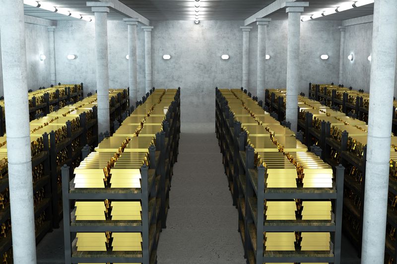 Rows of storage racks hold gold bars belonging to a customer in a brightly lit vault