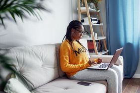 A woman sits at a computer, considering her finances.