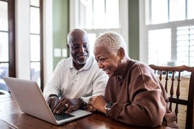 A couple reviews information on a laptop. 