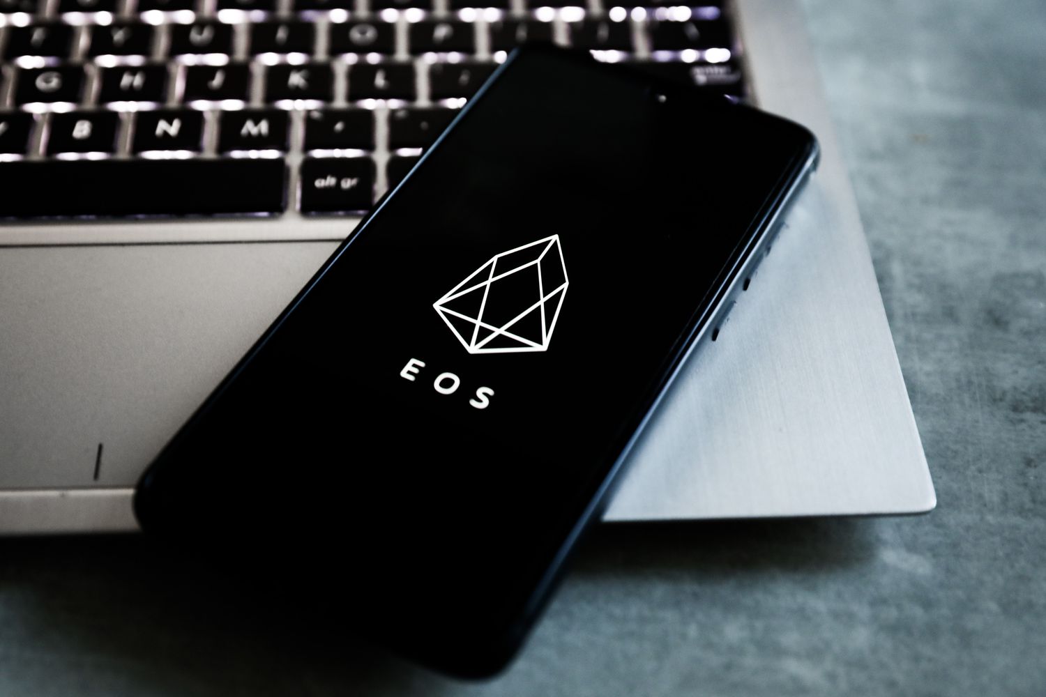 EOS cryptocurrency logo is displayed on a mobile phone screen photographed for illustration photo. 