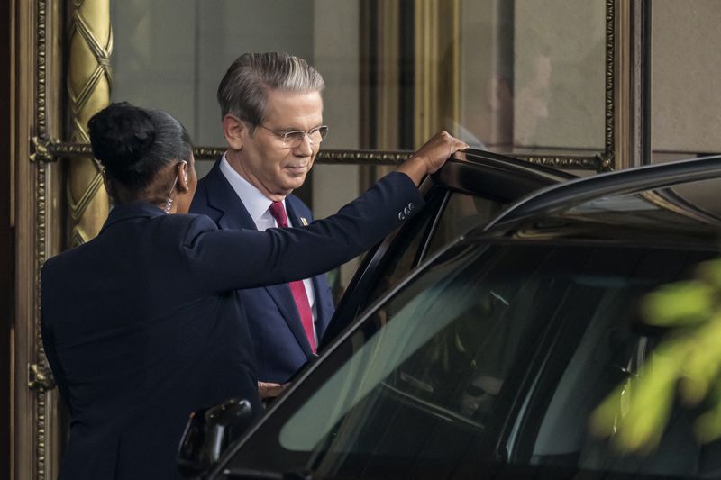 A person holds the door to a car open for Treasury Secretary Scott Bessent.