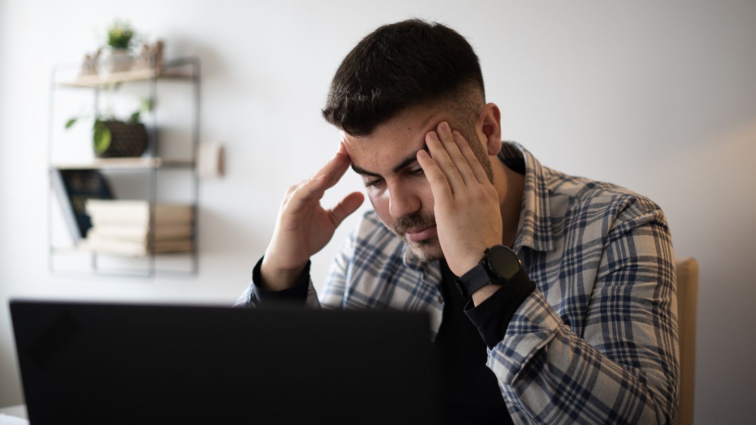 A speculative investor rubs their temple in angst after seeing a notice that their junk bond investment has gone into default.