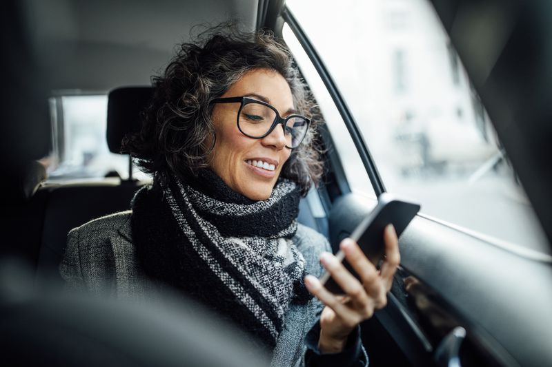 Middle-aged woman reading phone in car